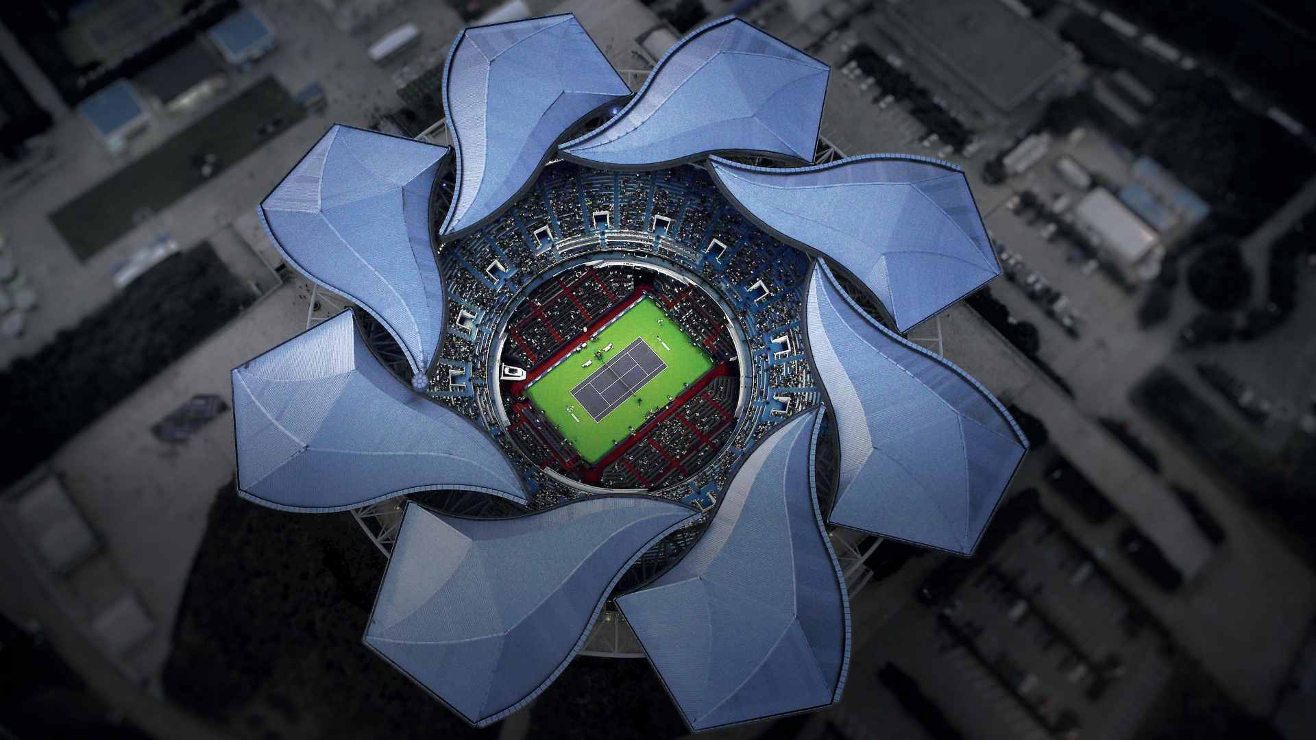 Aerial directly-overhead view of the Qizhong Forest Sports City Arena in Shanghai, highlighting its distinct flower-petal retractable roof open to reveal the tennis court inside
